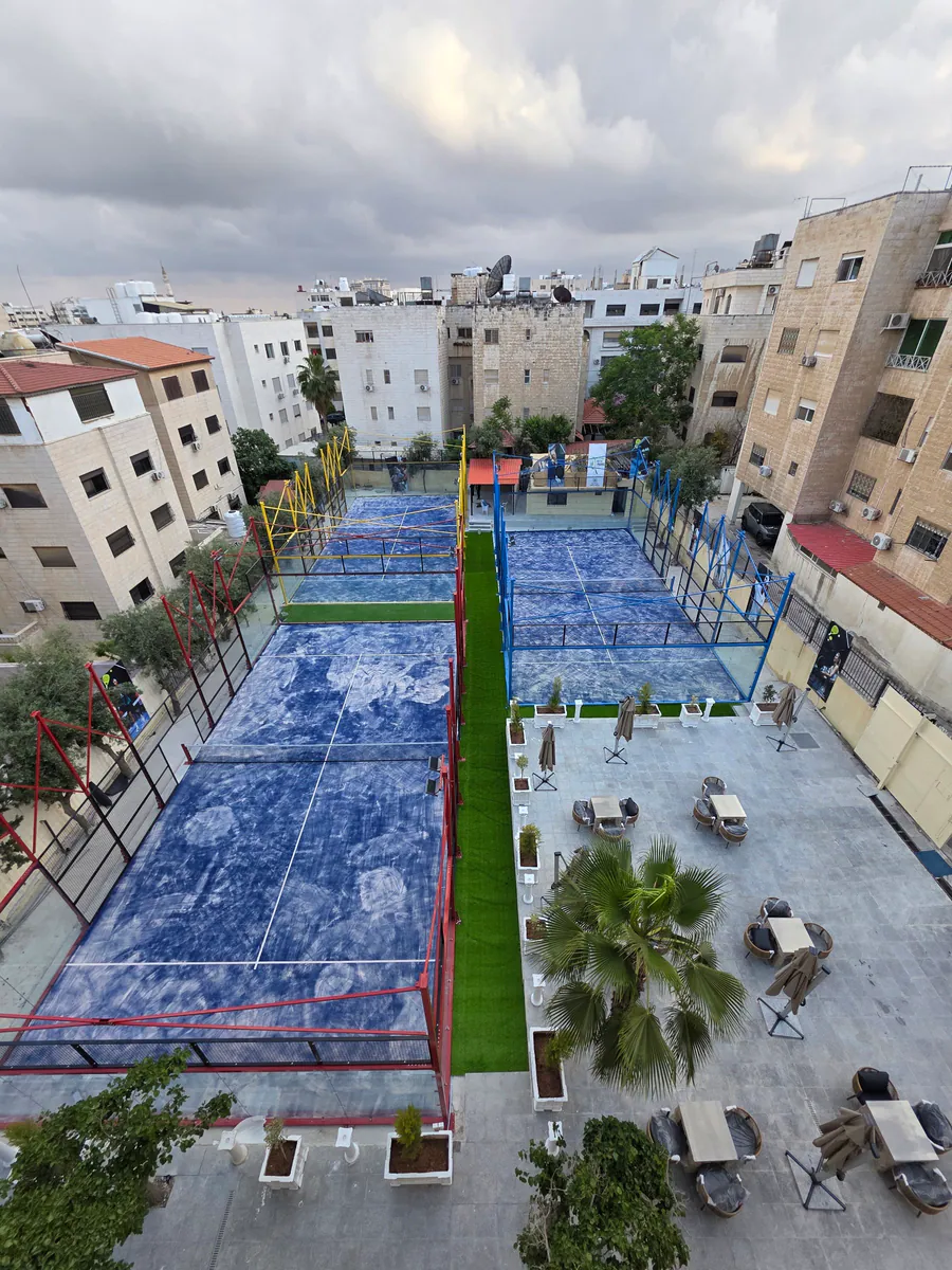 The Hub from above: three padel courts with red, yellow and blue frames beside the terrace