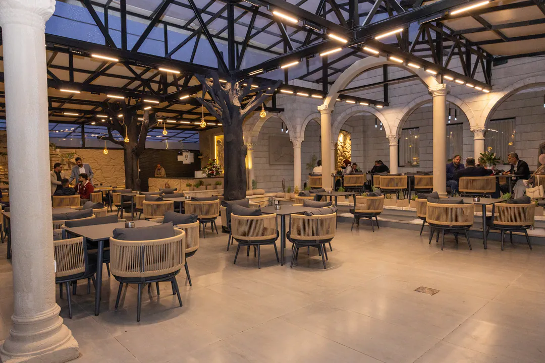 The Hub coffee house: armchairs and tables under stone arches and a steel and glass roof