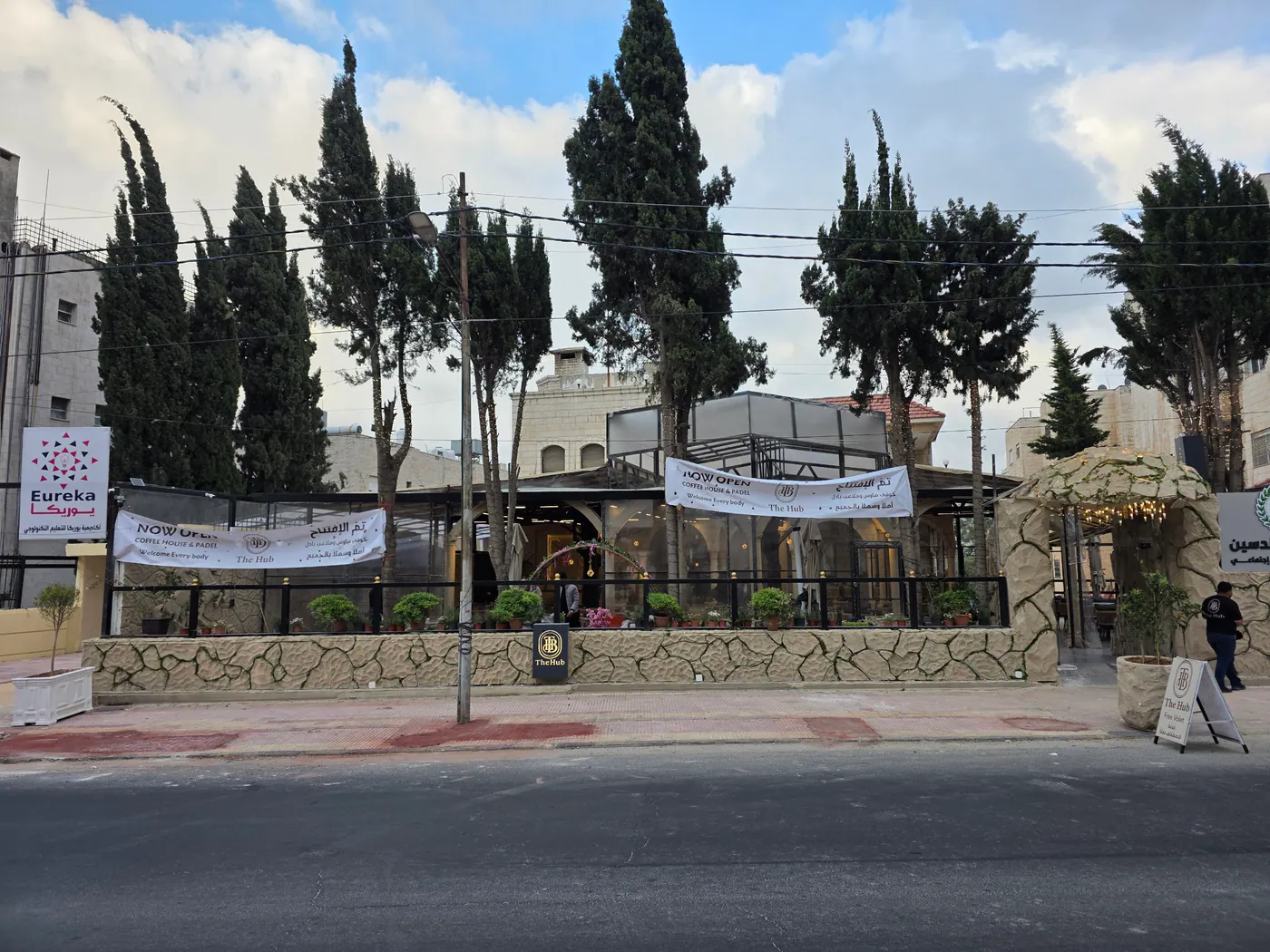 The Hub's street front on Abdullah Bin Rawahah Street, lined with cypress trees